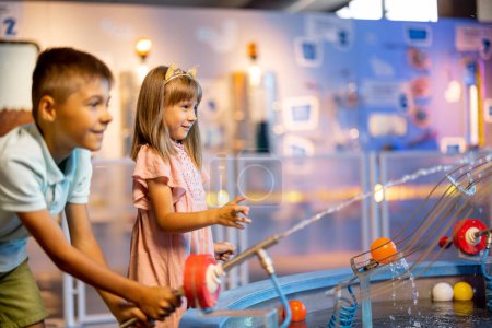 Foto de Niño y niña juegan con pelotas, aprendiendo fenómenos físicos de una manera interesante, divirtiéndose en un museo de ciencias con modelos interactivos - Imagen libre de derechos