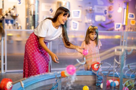 Photo for Mom with kids play with balls, learning physical phenomena in an interesting way, having fun in a science museum with interactive models - Royalty Free Image