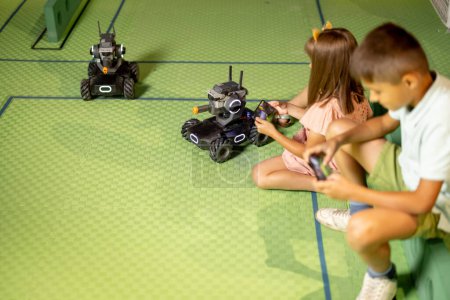 Foto de Niños jugando con coches robóticos controlándolos con controles remotos en un parque infantil en el museo de ciencias. Concepto de entretenimiento infantil y nuevas tecnologías - Imagen libre de derechos