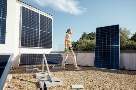 Foto de Hombre instalando paneles solares en la azotea plana de su casa para el autoconsumo. Concepto de energía renovable y sostenibilidad - Imagen libre de derechos
