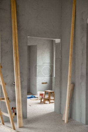Téléchargez les photos : Intérieur de la maison pendant le processus de rénovation. Préparation pour la peinture des murs. Intérieur vide sans personne. Seau avec peinture sur le sol - en image libre de droit