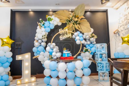decoración de cumpleaños de un año con globos blancos y azules desde diferentes ángulos