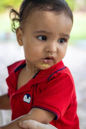 Téléchargez les photos : Mignon tout-petit bébé garçon manger de la crème glacée en apparence décontractée à l'extérieur - en image libre de droit