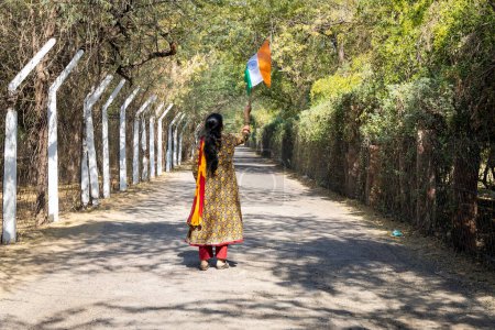 Téléchargez les photos : Jeune fille agitant le drapeau national tricolore indien à un endroit éloigné le jour de l'angle arrière - en image libre de droit