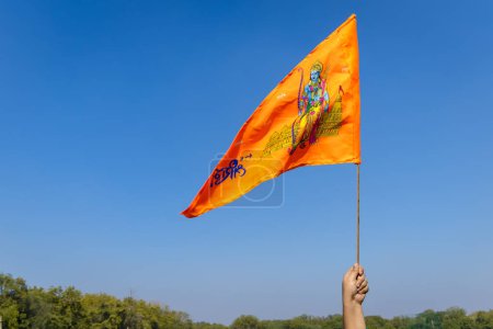 heilige Safran-Fahne mit Lord Rama Idol Holing in der Hand mit hellblauem Himmel Hintergrund am Tag