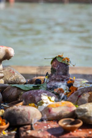 heiliger Gott shivalinga wird am Morgen von Gläubigen mit Blumen am Ufer des Flusses verehrt