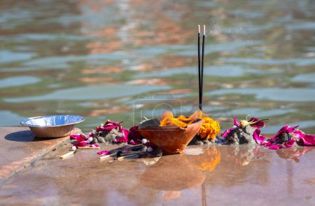Heilige Opfergaben von Gläubigen am religiösen Flussufer am Morgen aus flachem Winkel