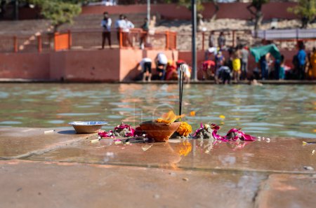 Heilige Opfergaben von Gläubigen am religiösen Flussufer am Morgen aus flachem Winkel