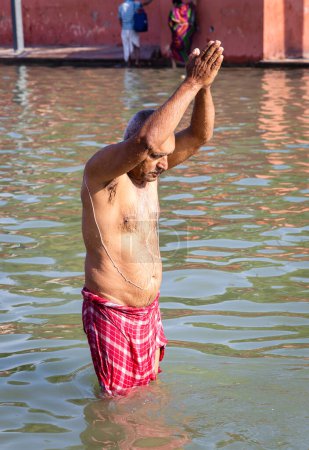 Gläubige beten nach dem morgendlichen Bad in heiligem Flusswasser aus flachem Winkel