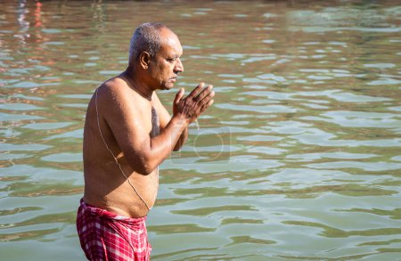 dévot prier après la baignade dans l'eau de la rivière sainte le matin sous un angle plat