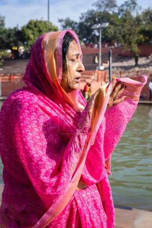 Téléchargez les photos : Dévot priant pour le dieu saint après s'être baigné dans l'eau de la rivière sainte le matin sous un angle plat - en image libre de droit