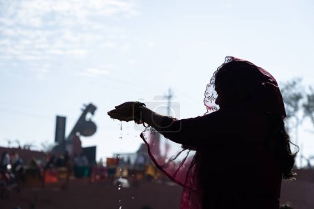backlit shot of young devotee praying for holy god after bathing in holy river water at morning