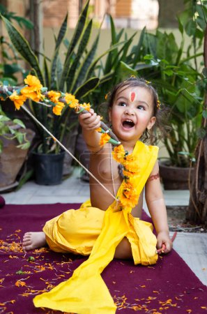 Téléchargez les photos : Portrait de mignon indien garçon robes comme seigneur rama avec arc à l'extérieur avec fond flou le jour - en image libre de droit