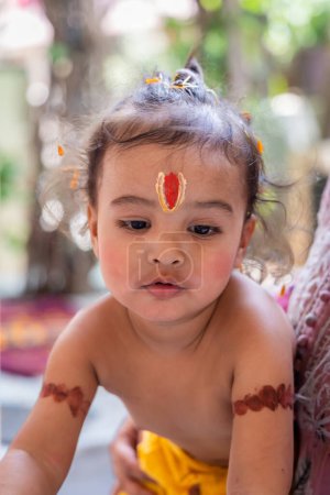 Téléchargez les photos : Mignon garçon indien avec saint symbole religieux sur la tête à l'extérieur avec fond flou - en image libre de droit