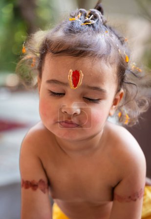 lindo ojo de niño indio cerrado con santo símbolo religioso en la cabeza al aire libre con fondo borroso