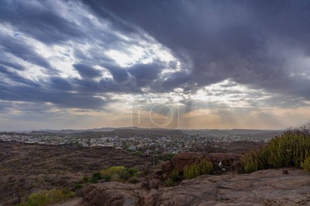 city view with dramatic sun beams orange sky at evening from mountain top image is taken at mehrangarh fort jodhpur rajasthan india.