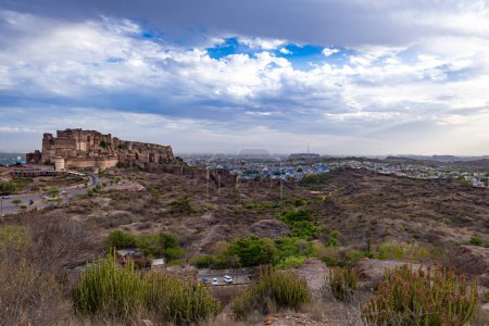 ancient historical fort with blue colored city houses and dramatic cloudy sky at evening image is taken at mehrangarh fort jodhpur rajasthan india.