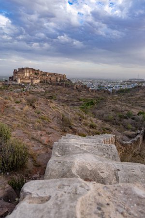 altes historisches Fort mit farbigen Stadthäusern und dramatischem bewölkten Himmel am Abend Bild wird bei mehrangarh Fort Jodhpur Rajasthan Indien aufgenommen.
