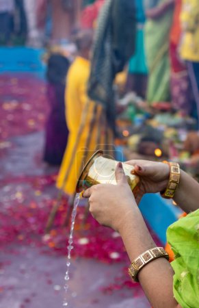 holy water offerings by indian devotee doing traditional rituals at chhath festival at morning