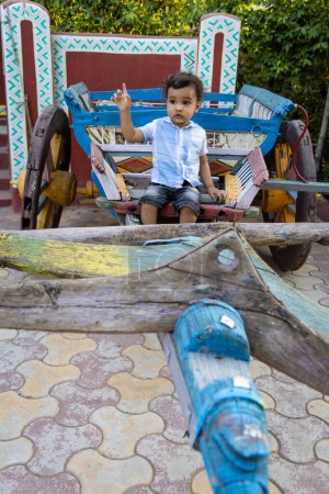 isolated toddler sitting at vintage wood bullock cart at outdoor at evening