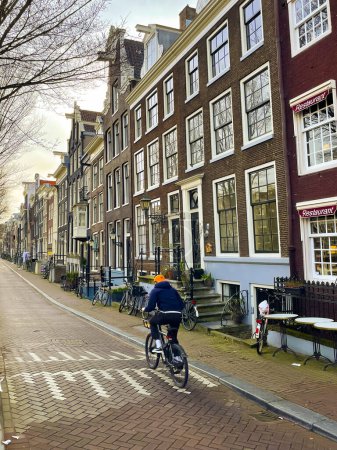 Téléchargez les photos : Homme méconnaissable en vélo dans une rue du centre historique d'Amsterdam. Mode de vie sain. - en image libre de droit