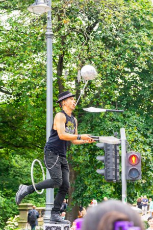 Téléchargez les photos : Édimbourg, Écosse, Royaume-Uni - 15 août 2023 : Un artiste de rue équilibre un cerceau, une balle et plusieurs couteaux dans le centre d'Édimbourg pendant le Fringe Festival. Plan vertical. - en image libre de droit