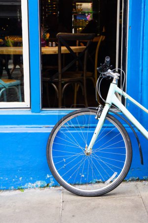Téléchargez les photos : Vélo bleu clair appuyé contre un mur bleu à Édimbourg. Tourné à la verticale. - en image libre de droit