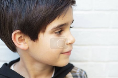 Téléchargez les photos : Portrait en gros plan d'un garçon caucasien de 7 ans regardant de côté avec une expression calme, sur fond blanc avec espace de copie. Horizontal. - en image libre de droit