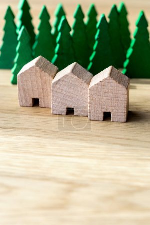 Three wooden row houses surrounded by tall trees in the background. Sustainable housing, real estate and insurance concepts. With copy space. Vertical.