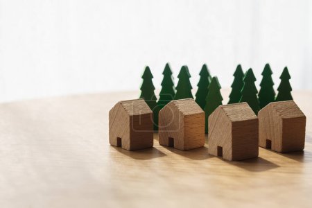Téléchargez les photos : Quatre maisons en bois entourées de grands arbres en arrière-plan. Logements durables, immobilier et concepts d'assurance. Avec espace de copie. Horizontal. - en image libre de droit