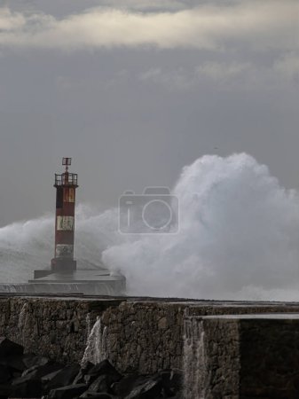 Foto de Salpicadura de ola grande. Ave muelle de la boca del río y faro en un día de mar agitado, al norte de Portugal. - Imagen libre de derechos