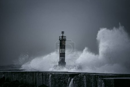 Große Welle plätschert. Ave Flussmündung Pier und Leuchtturm an einem rauen Tag auf See, nördlich von Portugal. Blautöne.