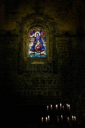 Foto de Monasterio de Jerónimos interior oscuro y venerativo que ve vidrieras que representan a Nuestra Señora y al Niño Jesús. - Imagen libre de derechos