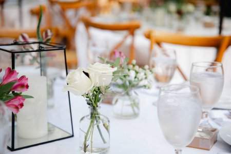 Photo for Backyard wedding reception - round tables with white tablecloths, vintage lanterns, roses and hyacinth,  and bentwood chairs - Royalty Free Image