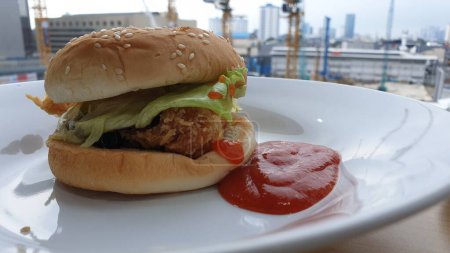 Téléchargez les photos : Un sandwich au poulet avec du ketchup sur une assiette blanche - en image libre de droit