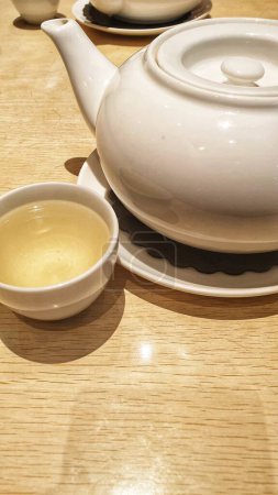 Foto de Un momento sereno capturado con una tetera y una taza de té humeante en una mesa, una invitación a saborear el calor de la relajación - Imagen libre de derechos