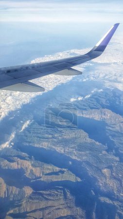 Photo for An exhilarating moment captured as an airplane's wing soars gracefully above a majestic mountain range, the thrill of travel - Royalty Free Image