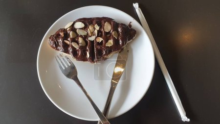 Téléchargez les photos : Savourez le moment avec une tranche décadente de gâteau au chocolat sur une assiette blanche immaculée, parfaitement complétée par une fourchette brillante - en image libre de droit