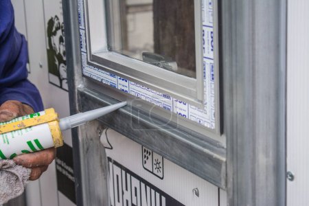 Téléchargez les photos : Ouvrier de la construction étanchéité fenêtre avec calfeutrage intérieur - en image libre de droit