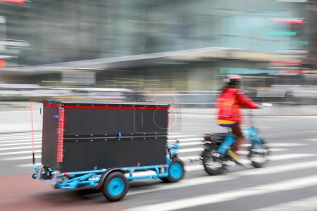 Téléchargez les photos : Livraison sur le vélo dans la circulation sur la route de la ville flou mouvement - en image libre de droit