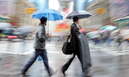 Téléchargez les photos : Les gens d'affaires marchant dans la rue par un mouvement de jour de pluie floue - en image libre de droit
