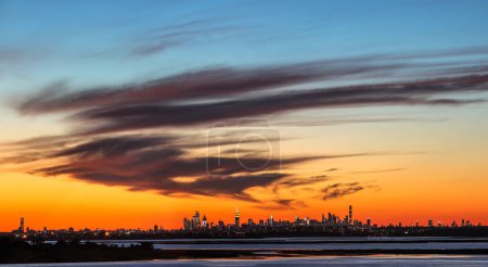 Téléchargez les photos : Paysage avec de l'eau et le panorama de New York avec un ciel couchant dynamique - en image libre de droit
