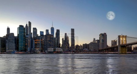 Téléchargez les photos : Vue panoramique New York centre ville Manhattan skyline la nuit avec des gratte-ciel et une grande lune dans le ciel - en image libre de droit