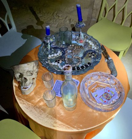 Foto de Calavera, alcohol, joyas, cartas en la mesa con sillas de colores alrededor. Una habitación donde una banda criminal de vacaciones. Retro ilustración - Imagen libre de derechos