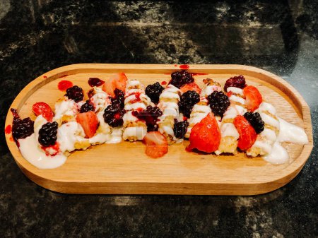 Käsekuchen mit saurer Sahne, Brombeeren und Erdbeeren. Appetitliches Dessert, Frühstück auf einem Holzteller. Idee für Restaurantmenüs oder Werbung 