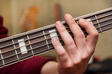 Foto de Close Up Shot Of Male Hand Playing 5 String Bass Guitar - Imagen libre de derechos
