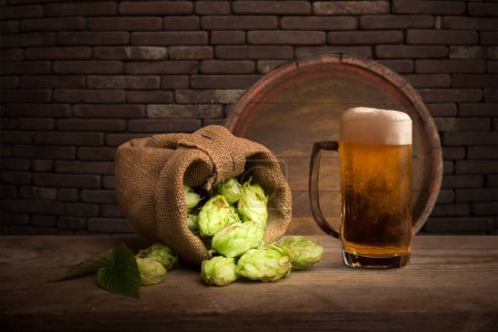 Téléchargez les photos : Tasse de bière, épis de blé, houblon et tonneau de bière sur un fond en bois. Photo de haute qualité - en image libre de droit
