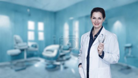 Photo for Doctor dentist woman with a tool in her hands stands against the background of the clinic. - Royalty Free Image