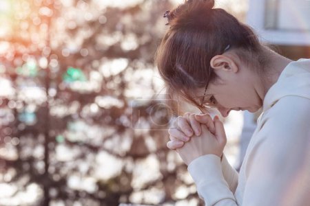 Photo for Woman praying with her head down on a blurred background. - Royalty Free Image
