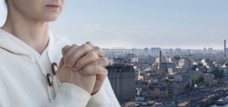 Photo for A woman prays against the backdrop of the city. - Royalty Free Image